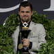 Magnus Carlsen stands with a trophy.